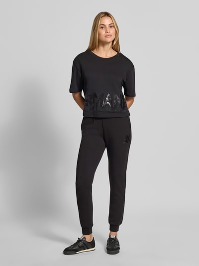 Frauenmodel trägt Slim Fit Sweatpants aus Viskose-Mix von Armani Exchange, czarne, elastyczne wykończenia, pas elastyczny, długość wewnętrzna nogawki w rozmiarze S: 74 cm, mieszanka wiskozy, krój slim fit, Ganzkörperansicht von vorne