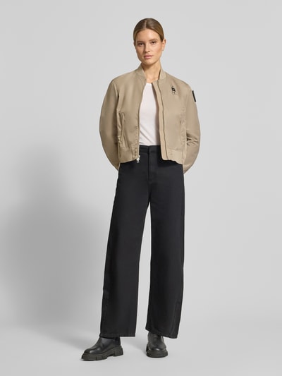 Frauenmodel trägt Bomberjacke mit Reißverschlusstaschen Modell 'LAURIE' von Blauer Usa in Beige, Loose-Fit, Stehkragen, Ganzkörperansicht von vorne