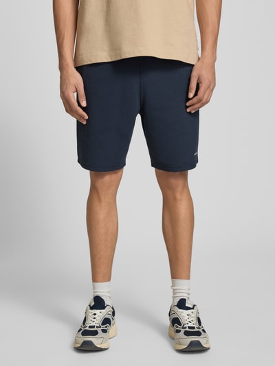 Männermodel trägt Straight Fit Shorts mit Strukturmuster von G-Star Raw in Dunkelblau, Elastischer-Material-Mix mit Logo-Detail, Ganzkörperansicht von vorne.