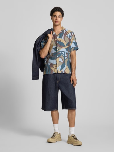 Männermodel trägt Regular Fit Freizeithemd im Allover-Look Modell 'TAVIRA MARSHALL' von Jack & Jones in Blau-, Beige- und Grüntönen, kombiniert mit dunkler Jeansshorts, Viskose-Mix, Reverskragen, Nahaufnahme Ganzkörperansicht von vorne.