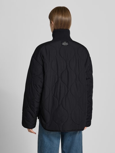 Vrouwenmodel draagt gewatteerd jack met doorgestikte naden, opstaande gebreide kraag, ritssluiting, steekzakken, Model 'SERENA' van JJXX, loose fit, zwart, ruglengte maat S 89 cm, schouderbreedte 58 cm, borstwijdte 57 cm, mouwlengte 55 cm, achterkant, Ganzkörperansicht Rückansicht.