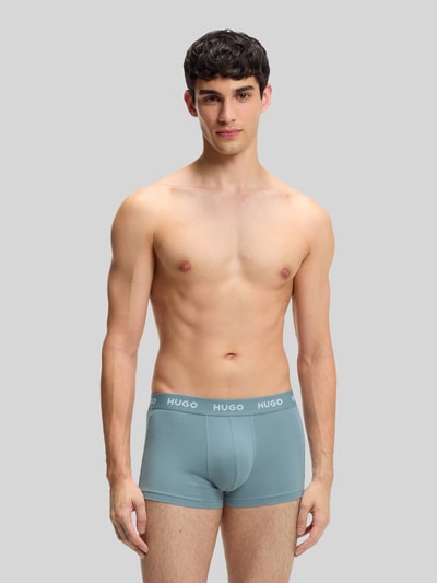 Männermodel trägt Slim Fit Trunks aus Baumwoll-Mix im 3er-Pack Modell 'PACK' von HUGO, Optik: Unifarben, Label-Schriftzug, Bundabschluss: Elastisch, Materialverarbeitung: Stretch-Jersey, Multipack:3er-Pack, Ganzkörperansicht von vorne.