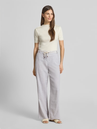 Modelka nosi Hose aus Leinen-Baumwoll-Mix mit Bindegürtel von Christian Berg Woman, jasnoszary kolor, szeroka nogawka, pasek, kieszenie, Szerokość w rozmiarze 36: 41 cm, długość nogawki wewnętrznej 81 cm, lniano-bawełniana struktura, widok całej sylwetki z przodu.