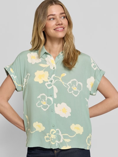 Vrouwenmodel draagt Bluse aus Viskose mit fixiertem Ärmelaufschlag van JAKE*S STUDIO WOMAN, lichtgroen met bloemenprint, recht model, kentkraag, knoopsluiting, mouwen met vaste omslag, zuiver viscose, ruglengte maat 36: 62 cm, mouwlengte maat 36: 13 cm, close-up bovenlichaam.