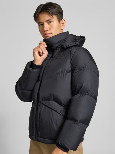 Männermodel trägt Regular Fit Daunenjacke mit Kapuzenkragen von Marc O'Polo DENIM in Schwarz, glatte Oberfläche, Nahaufnahme Oberkörper.