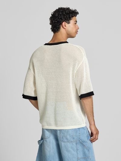 Männermodel trägt T-Shirt in Häkel-Optik mit V-Ausschnitt von KARL KANI, Baumwoll-Mix, Loose-Fit, Label-Stitching, Rückansicht, Rückenlänge 68 cm bei Größe M.