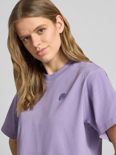 Modelka kobieca nosi damski t-shirt Relaxed Fit T-Shirt aus reiner Baumwolle Modell 'VINTAGE TEE_B_1' od Hugo Blue, jednokolorowy, z okrągłym dekoltem, krótki rękaw, wykonany z czystej bawełny, naszywka z logo na przodzie, kolor jasnofioletowy, widoczna gładka tekstura, efekt: jednolity kolor, krój relaxed fit, z przodu naszywka z logo, półzbliżenie na górną część ciała