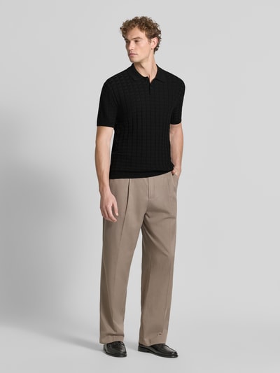 Männermodel trägt Regular Fit Poloshirt aus Viskose-Mix Modell 'Maglia' von Armani Exchange in Schwarz mit Stepp- und Strick-Optik, Kurzarm, Ganzkörperansicht von vorne.