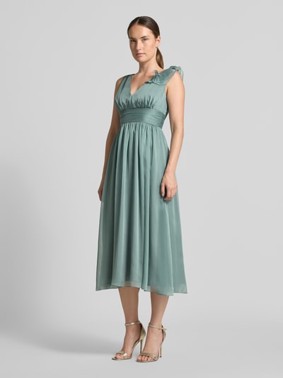 Frauenmodel trägt Cocktailkleid mit V-Ausschnitt von Swing in Taillierter Passform mit Raffungen, Taillenband, Volants, Reißverschluss hinten, Midikleid in sanftem Grün, glatte Textur, Ganzkörperansicht von vorne.