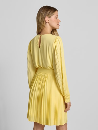 Männermodel trägt Cocktailkleid mit Plisseefalten Modell 'Celina' von GUIDO MARIA KRETSCHMER WOMAN, jasny żółty, krój slim fit, dekolt okrągły, pasek, plisowana spódnica, długość pleców w rozmiarze 36: 85 cm, szerokość w rozmiarze 36: 38 cm, długość rękawa w rozmiarze 36: 65 cm, tylny rozcięcie na guziczek, całościowy widok z tyłu
