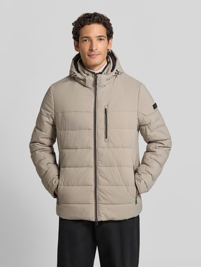 Männermodel trägt Steppjacke mit Zweiwege-Reißverschluss von bugatti in Beige mit Kapuze, Reißverschlusstaschen, krój regular fit, Ganzkörperansicht von vorne, długość tyłu w rozmiarze 50: 75 cm, szerokość ramion w rozmiarze 50: 49 cm, szerokość w klatce piersiowej w rozmiarze 50: 60 cm, długość rękawa w rozmiarze 50: 67 cm