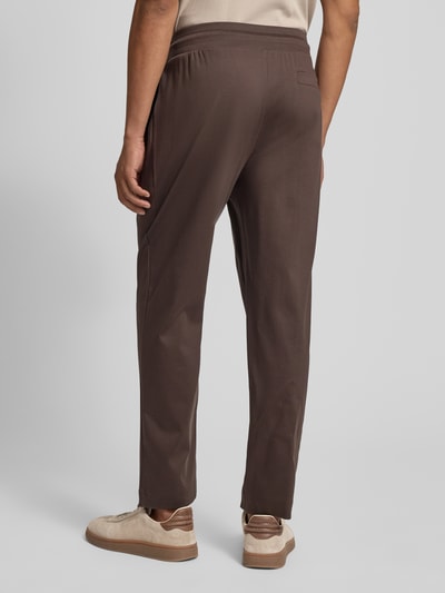 Männermodel trägt Sweatpants mit Eingrifftaschen Modell 'Josemiguel' von JOOP! Collection in Braun, Straight Fit, Ganzkörperansicht Rückansicht.