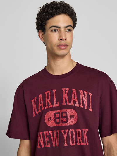 Männermodel trägt Oversized Fit T-Shirt mit Logo-Print Modell 'Heritage' von KARL KANI aus Reine Baumwolle, Rundhalsausschnitt, Nahaufnahme Oberkörper.