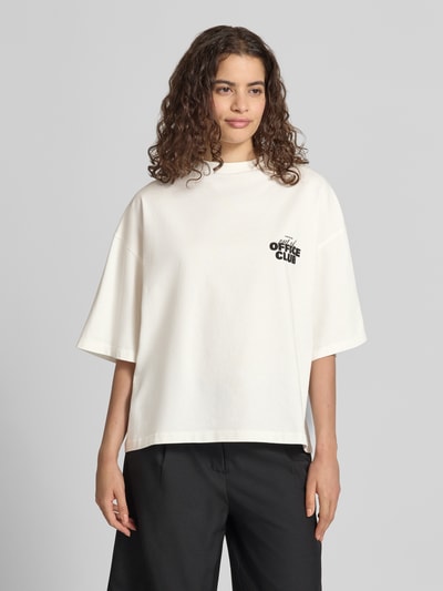 Kobiece modelka nosi Cropped Oversized T-Shirt mit Label-Print od Karo Kauer z bawełny, krój oversized, okrągły dekolt, skrócona długość, nadruk z logo z przodu i z tyłu, damski t-shirt, widok całej sylwetki z przodu.