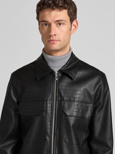 Męski model nosi Slim Fit Jacke in Leder-Optik Modell 'GIUBBINO' od Antony Morato; czarna, ze stójką, faktura skóry; zbliżenie na górę ciała.