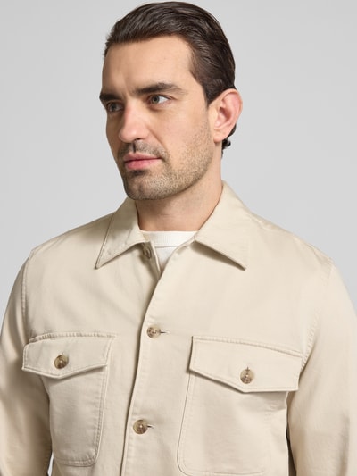 Męski model nosi Regular Fit Hemdjacke aus Baumwoll-Mix von Marc O'Polo, jednokolorowy beż, splot twill, krój regular fit, wykładany kołnierz, listwa guzikowa, kieszeń na piersi i wpuszczane kieszenie, mieszanka bawełny, zbliżenie na górną część ciała