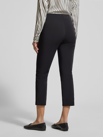 Männermodel trägt czarne, dopasowane spodnie Schmale Schlupfhose aus Techno Cotton Superstretch von Raffaello Rossi, krój slim fit, długość 7/8, Szerokość w rozmiarze 36: 36 cm, długość nogawki od wewnątrz w rozmiarze 36: 61 cm, Ganzkörperansicht Rückansicht.