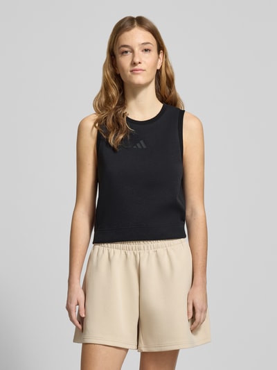 Frauenmodel trägt Regular Fit Top mit Logo-Print von adidas Sportswear in Schwarz, elastischer Material-Mix, Rundhalsausschnitt, Ganzkörperansicht von vorne.