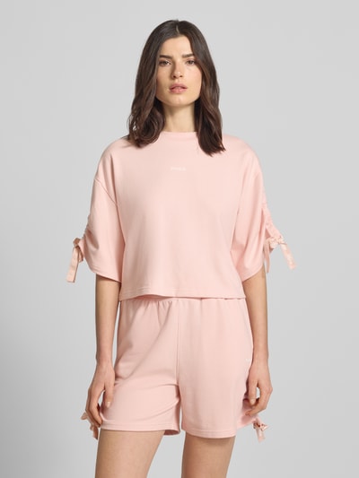 Frauenmodel trägt Boxy Fit Pyjama-Oberteil mit Baumwoll-Anteil von HUGO in Optik: Unifarben, Sweat, Label-Print, Raffungen, Ganzkörperansicht von vorne.
