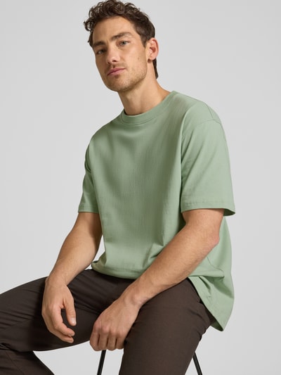 Männermodel trägt Relaxed Fit T-Shirt aus reiner Baumwolle Modell 'MAARKOS HEAVY WEIGHT' von Armedangels in Mintgrün, unifarben, Kurzarm, Logo-Stitching, Jersey-Textur; Nahaufnahme Oberkörper.