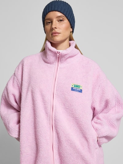 Vrouwenmodel draagt oversized jas met opstaande kraag, teddyfleece, rits, labeldetail, steekzakken, model 'HOKTOWN' van American Vintage, vooraanzicht bovenlichaam