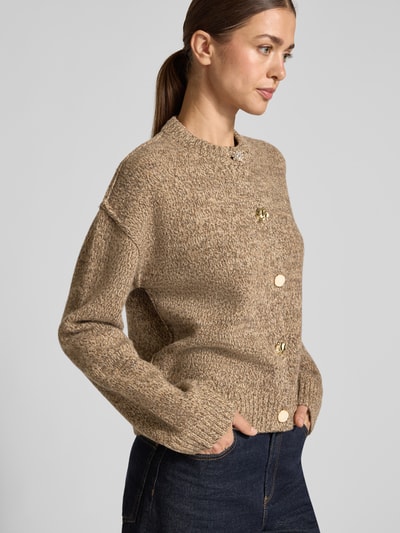 Modelka kobieca nosi Relaxed Fit Strickjacke aus reiner Wolle in Strick-Optik od Christian Berg Woman, melanż beżowy, grube dzianinowe faktury, prążkowane zakończenia, złote guziki, długie rękawy, obniżone ramiona, widoczny cały przód, widok z przodu, kontekst: damska marynarka, czysta wełna, długość tyłu 55 cm, długość rękawa 54 cm, relaxed fit, prążkowane wykończenia, pełne zapięcie na guziki, długi rękaw, obniżone ramiona, strick-optik, oni Ganzkörperansicht von vorne.