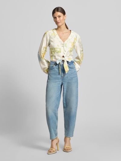 Frauenmodel trägt Cropped Bluse aus Leinen-Viskose-Mix Modell 'SHIRLEY' von Guess in Creme mit gelben Blumen, V-Ausschnitt, Ganzekörperansicht von vorne.
