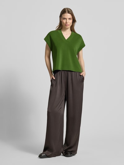 Vrouwenmodel draagt Relaxed fit T-shirt met lyocell-aandeel model 'Tencel' van Scotch & Soda in groen, kapmouwen, V-hals, elastische materiaalmix. Ganzlichaamsaanzicht van voren.