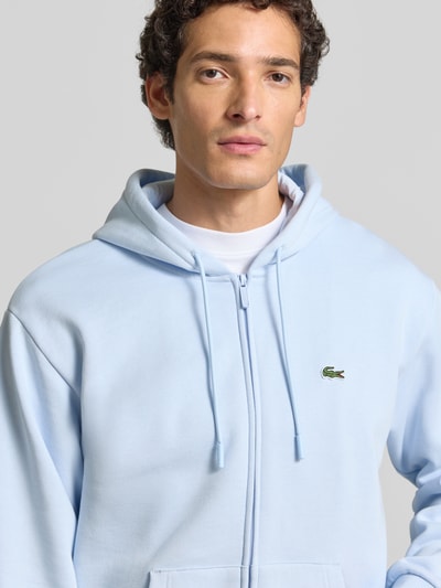 Männermodel trägt Regular Fit Sweatjacke aus Baumwoll-Mix von Lacoste in Hellblau mit glatter Textur, Nahaufnahme Oberkörper. Herren Sweatjacke von Lacoste.