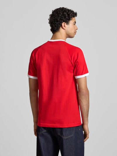 Männermodel trägt T-Shirt mit Label-Stitching von adidas Originals in Rot mit weißen gerippten Abschlüssen aus reiner Baumwolle, Regular-Fit, Rundhalsausschnitt, Rückenlänge bei Größe M 73 cm, Ganzkörperansicht Rückansicht.