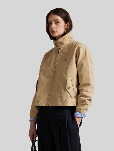 Vrouwenmodel draagt Regular Fit Blouson uit pure katoen van Polo Ralph Lauren in effen beige met logo-detail, zijflapzakken, elastische boorden, lange mouwen, geheel vooraanzicht bovenlichaam.