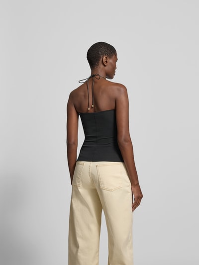 Frauenmodel trägt Neckholder-Top mit Zierstein von Nanushka, schwarze Farbe, eng anliegende Passform, Rückenlänge 31 cm, Ganzkörperansicht Rückansicht.