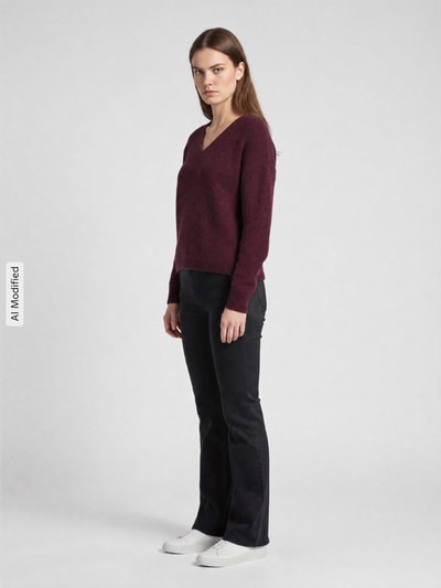 Modelka kobieca ma na sobie Relaxed Fit Pullover mit V-Ausschnitt od ONLY, ciemnoczerwony sweter z dekoltem w serek, gładka faktura, damski sweter ONLY, widok całej sylwetki z przodu, KI-modifiziertes Bild