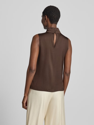 Frauenmodel trägt Blusentop mit Stretch-Anteil von DRYKORN in Braun, ärmellos, Satin, Rollkragen, verlängerte Rückseite, Ganzkörperansicht Rückansicht.