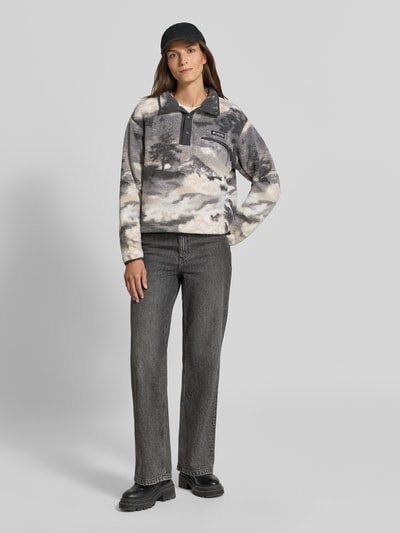 Vrouwenmodel draagt Fleeceshirt met opstaande kraag en labelpatch Model 'Helvetia II' van Columbia in zwart-wit tinten, rechte fit, wolachtige textuur, borstzak met ritssluiting, geheelopname van voren.