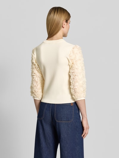 Männermodel trägt Strickshirt aus Viskose-Mix mit floralen Applikationen von Zero, kremfarbener Stoff, Ärmel mit 3D-Blumenstruktur, krój dopasowany, okrągły dekolt, długość pleców w rozmiarze 36: 48 cm, długość rękawa w rozmiarze 36: 43 cm, Ganzkörperansicht Rückansicht