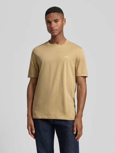 Männermodel trägt Regular Fit T-Shirt aus reiner Baumwolle Modell 'DERO222' von HUGO in Beige, unifarben, Label Print, Ganzkörperansicht von vorne