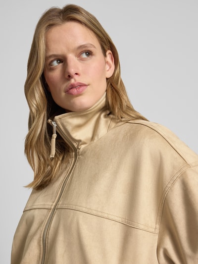 Frauenmodel trägt Jacke in Leder-Optik mit Reißverschluss und Eingrifftaschen von Gina Tricot, beige, glatte Textur, Nahaufnahme Oberkörper.