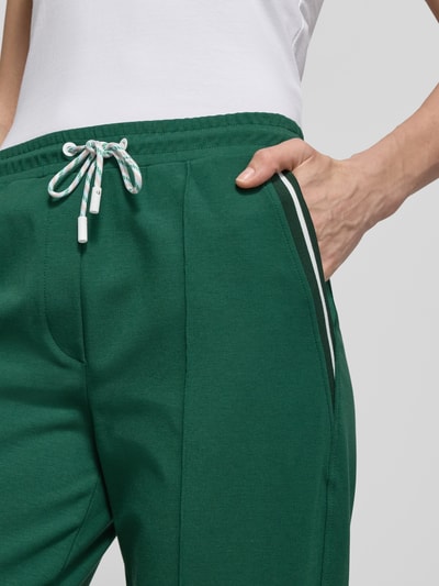 Frauenmodel trägt Straight Fit Stoffhose mit Ziernähten von Marc Cain in Grün, Elastischer-Baumwoll-Mix mit Modal-Anteil, nahaufnahme Oberkörper. 