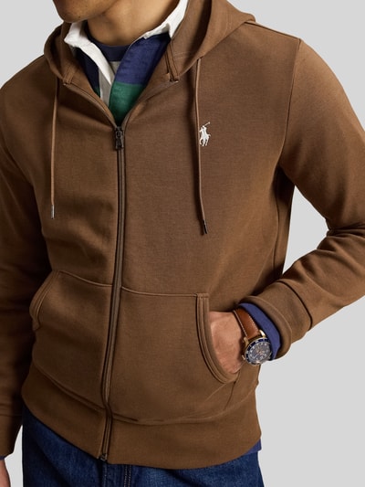 Męski model nosi Regular Fit Sweatjacke aus Baumwoll-Mix von Polo Ralph Lauren, brązowa, gładka faktura, kieszenie, zamek, bluza rozpinana, mieszanka bawełny, z przodu, zbliżenie na górną część ciała.