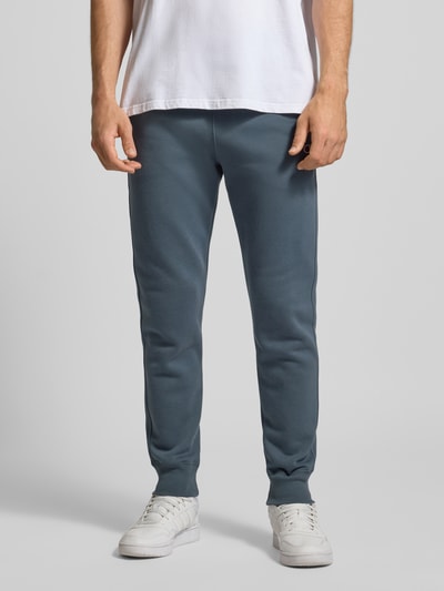 Männermodel trägt Sweatpants mit elastischem Bund und Label-Stitching von CHAMPION aus Baumwoll-Mix, Regular-Fit, Ganzkörperansicht von vorne.