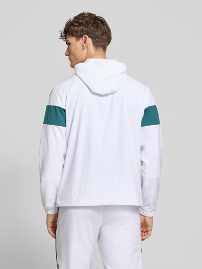Männermodel trägt weiße Regular Fit Jacke mit grünem Logo-Stitching, Kapuze und Reißverschluss, Modell 'Caspio' von SERGIO TACCHINI, Ganzkörperansicht Rückansicht. Elastischer Material-Mix, elastische Ärmelabschlüsse, Eingrifftaschen und sportliches Design erkennbar.