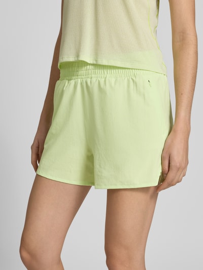 Frauenmodel trägt Regular Fit Shorts mit elastischem Bund Modell 'Kout' von Salomon in Hellgrün, glatter Stoff, integrierter Slip, Nahaufnahme Oberkörper. Damen Shorts, elastischer Bund, Bundweite S: 36 cm, Innenbeinlänge S: 10 cm.