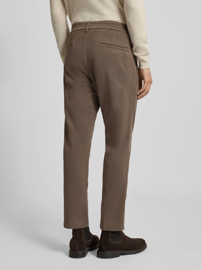 Męski model nosi Regular Fit Hose mit Bundfalten Modell 'CHASY' od Drykorn, brązowy lyocell-bawełna stretch, widok całej sylwetki z tyłu.