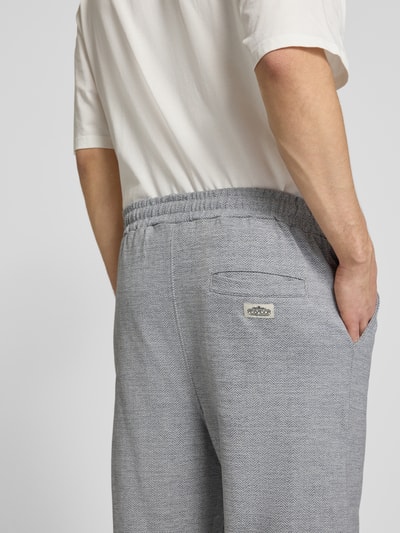 Männermodel trägt Track Pants mit Logo-Stitching Modell 'Skagen' von Pegador aus Reine Baumwolle, Loose-Fit, Gesäßleistentasche, Nahaufnahme Rückansicht.