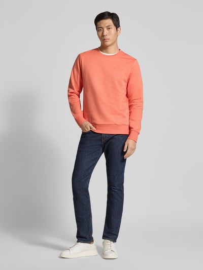 Männermodel trägt Regular Fit Sweatshirt aus Baumwoll-Mix von Tom Tailor, Optik: Unifarben, Label-Print, Crew Neck, Langarm, gerippte Abschlüsse, Materialverarbeitung: Sweat, Farbe: Koralle, Ganzkörperansicht von vorne.