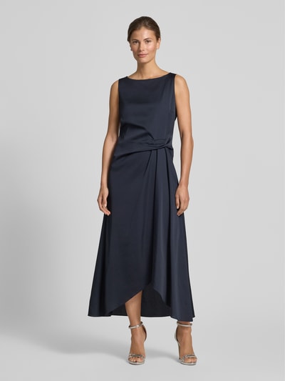 Frauenmodel trägt Cocktailkleid mit asymmetrischem Saum von Vera Mont in Dunkelblau, Taillierter Schnitt, U-Boot-Ausschnitt, Raffung an der Taille, Rückseitiger Reißverschluss, Midikleid, glatte Textur, Rückenlänge bei Größe 36: 128 cm, Brustweite: 45 cm, Ganzkörperansicht von vorne.