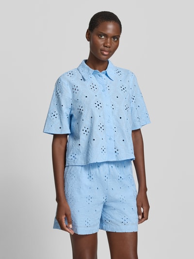 Kobiece modelka nosi bluzka koszulowa Relaxed Fit Hemdbluse aus reiner Baumwolle Modell 'ELIZA' von Vero Moda, efekt: jednolity kolor, haft angielski, kołnierzyk koszulowy, dekolt w serek, listwa guzikowa, rękaw o dł. 1/2, bawełna, jasnoniebieska faktura, Ganzkörperansicht von vorne.