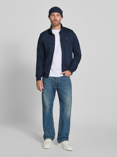 Mężczyznamodel nosi Regular Fit Sweatjacke aus Baumwoll-Mix von s.Oliver RED LABEL, granatowa, biała koszulka, dżinsy, białe buty, całościowy widok z przodu