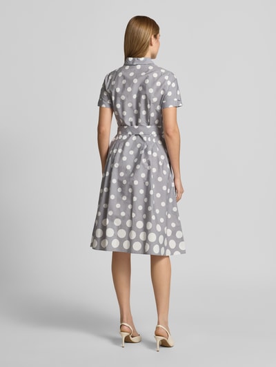 Frauenmodel trägt Hemdblusenkleid mit Bindegürtel von More & More, Reine Baumwolle, A-Linie, Midikleid, graue Grundfarbe mit weißen Punkten, Rückenlänge bei Größe 36: 110 cm, Brustweite 50 cm, Ärmellänge 20 cm, Ganzkörperansicht Rückansicht.